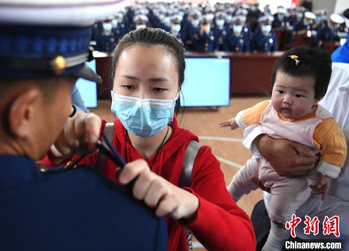 新消防員楊振的妻子彭莉與女兒現(xiàn)場見證丈夫加入“火焰藍”的神圣時刻?！⒅铱?攝